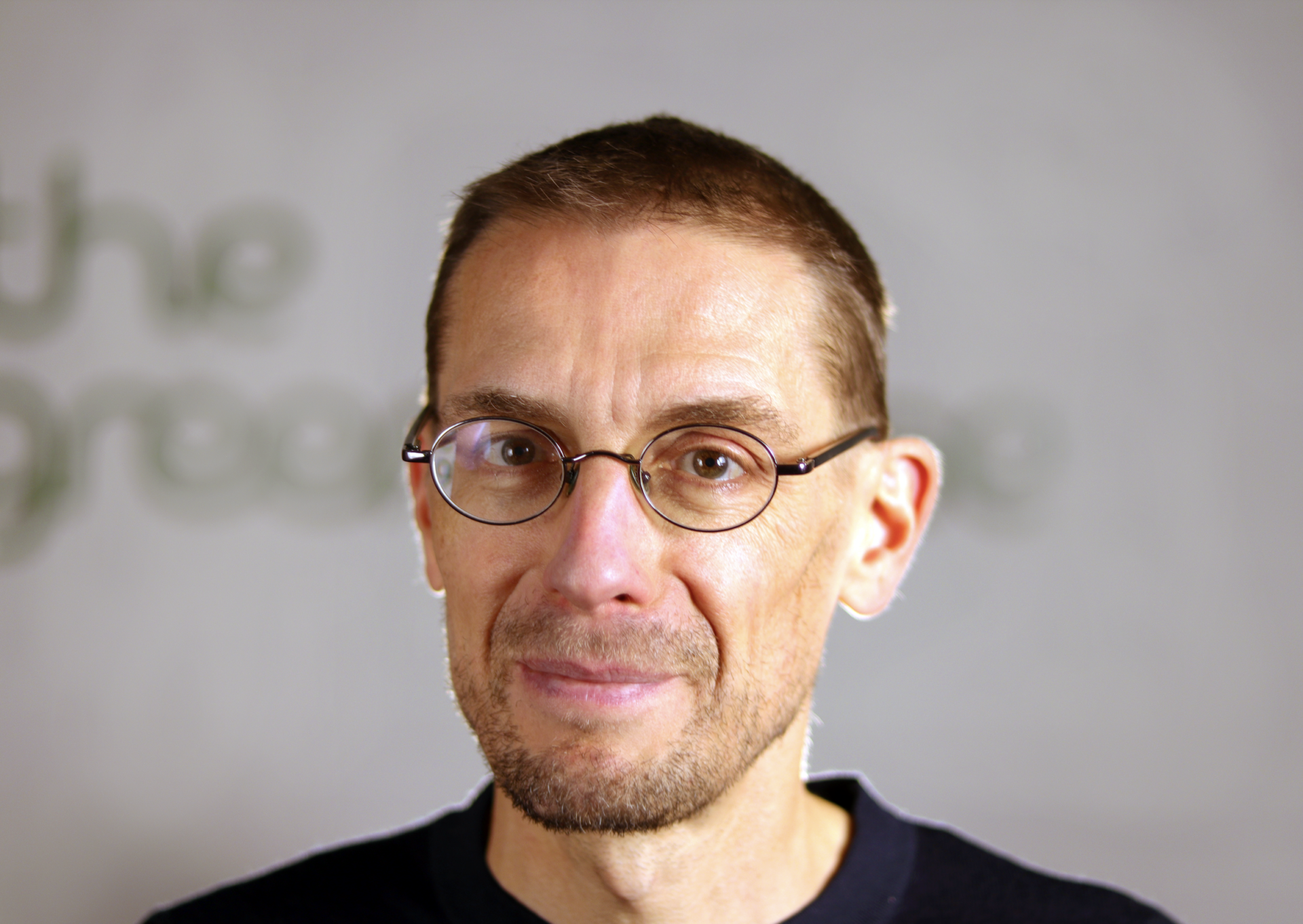 Smiling man with glasses in black shirt